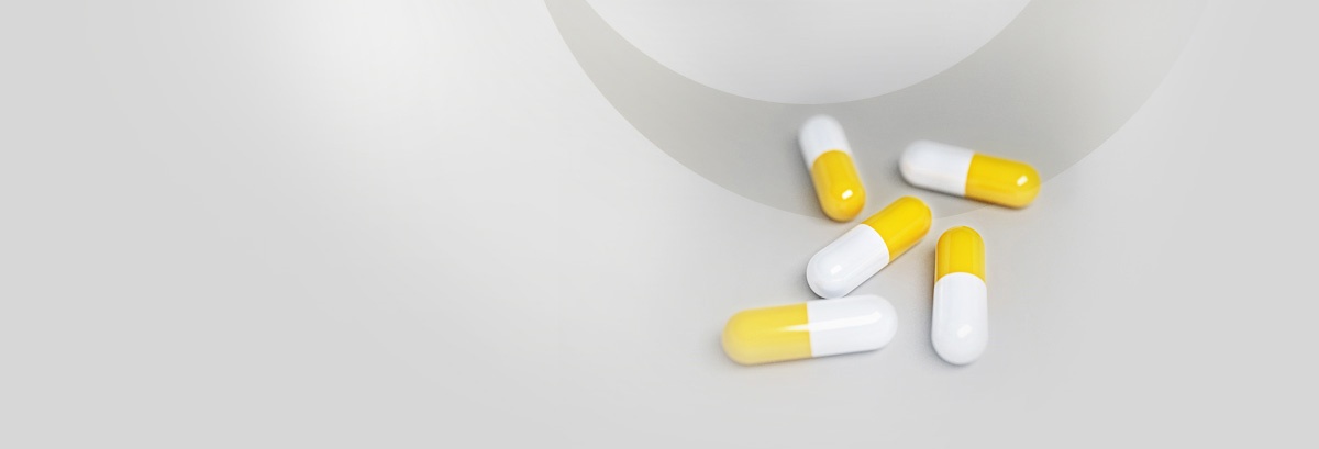 Five yellow and white capsules scattered on a light gray surface, minimal and clean mood